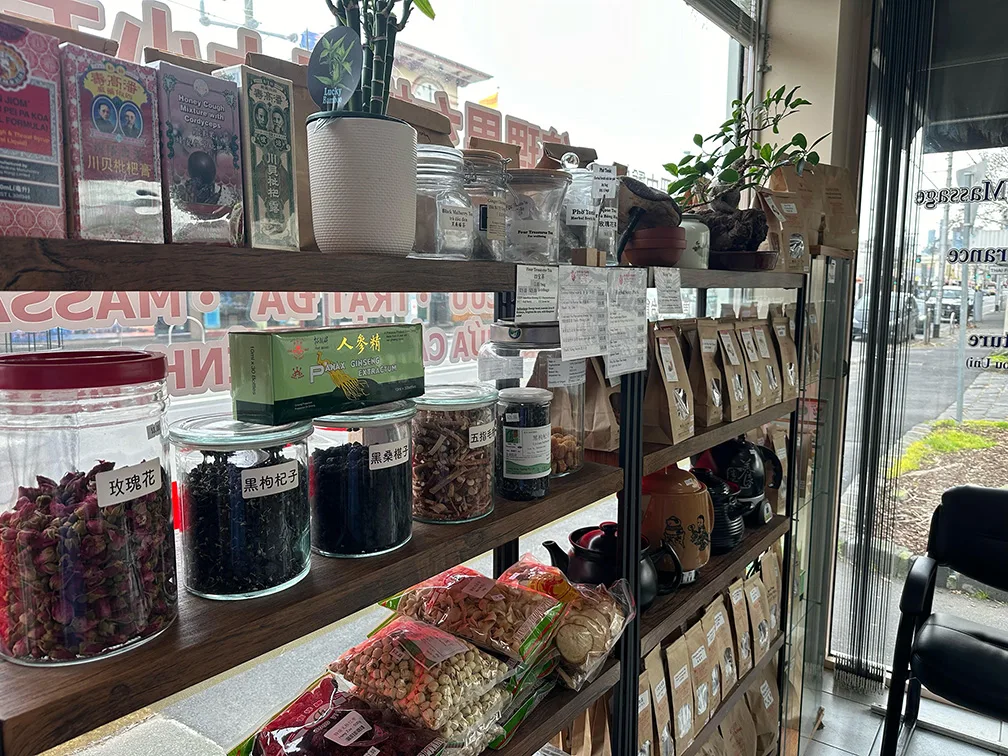 Glass apothecary jars with rose buds and goji on timber shelving