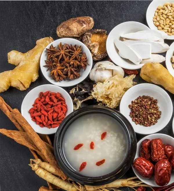 Flat-lay of TCM herbs around a black congee pot